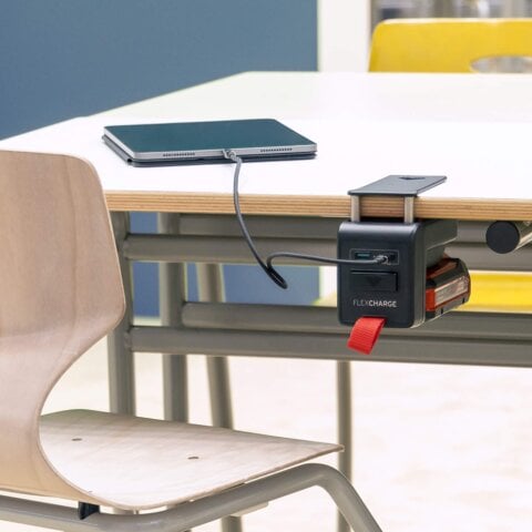 Schultisch mit einem angeklemmten FLEXCHARGE Akkuladegerät, das ein iPad auflädt
